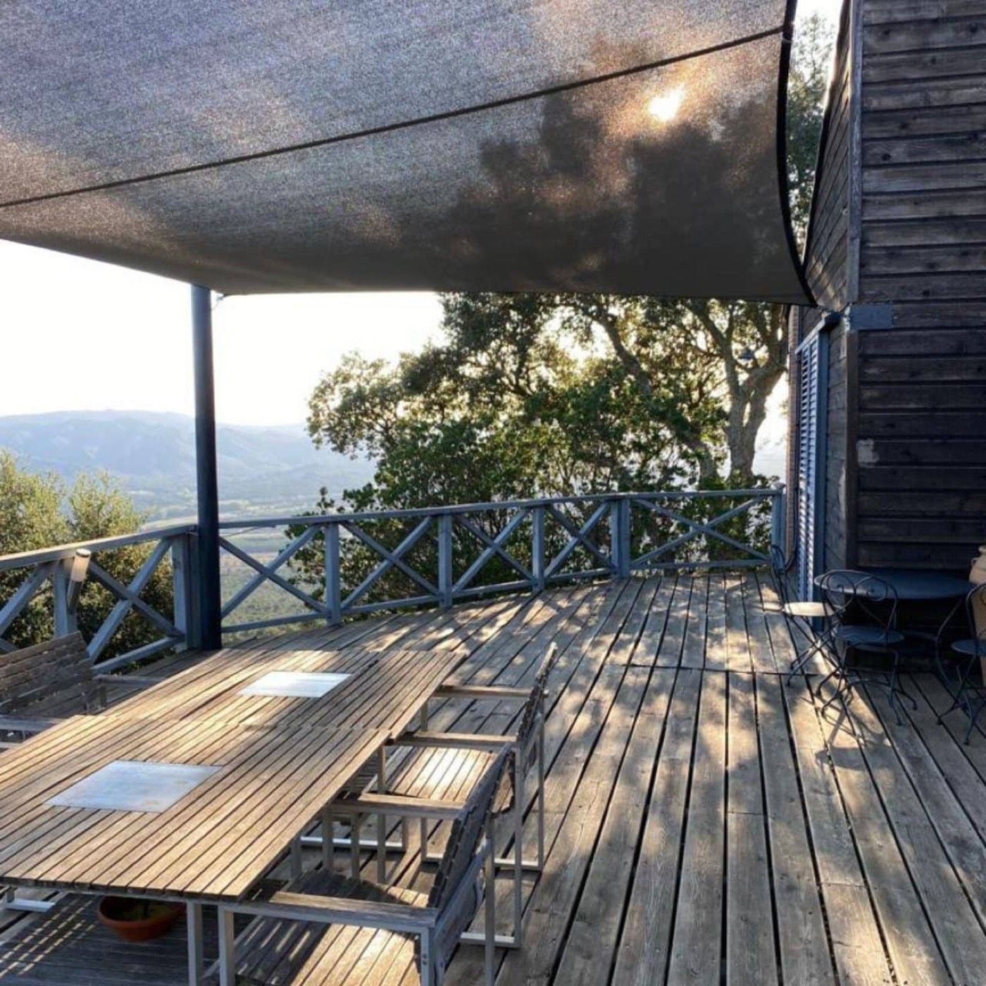 Toldo vela sobre una tarima de madera con vistas al bosque